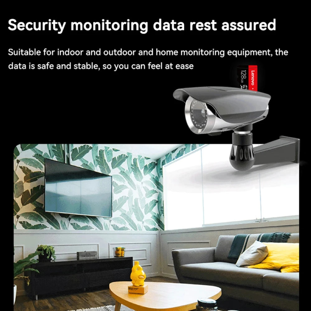 A home interior with a wall-mounted security camera in the living room records every moment securely with a Lenovo 128GB Micro TF Card - Fast 100MB/s Speed. The space boasts a sofa, colorful pillows, and a wooden coffee table with tea essentials against leaf-patterned wallpaper.