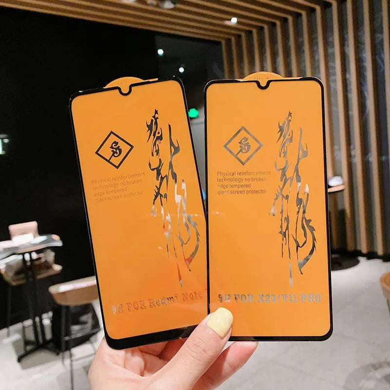 A hand holds two LITBOY Tempered Glass Protectors with black edges and Chinese calligraphy for Xiaomi devices in a modern café with wooden accents and tables, showcasing premium screen protection.