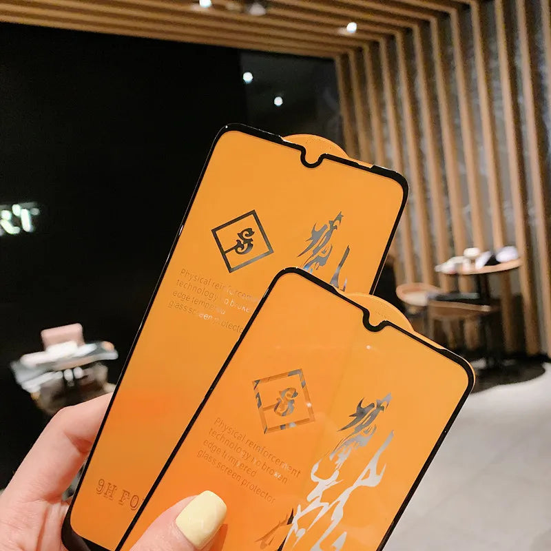 A hand displays two LITBOY Tempered Glass Protectors with black edges, designed for Xiaomi devices, inside a modern room featuring wooden panels, a table, and chairs in the background.