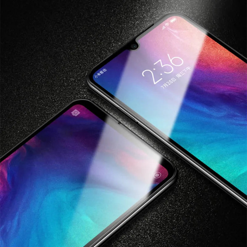 Two Xiaomi smartphones with vibrant displays lie on a dark surface, one showing 2:36 and Chinese text. Reflections hint at the importance of using a quality screen protector like the LITBOY Tempered Glass Protector for Xiaomi devices.