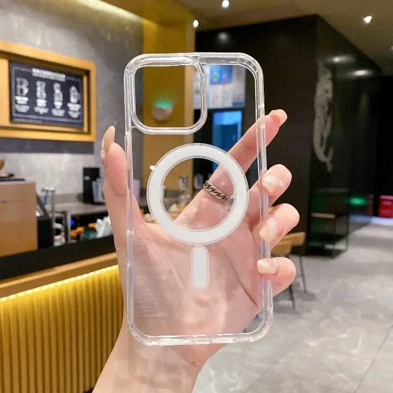 Hand holding a transparent PC phone case with MagSafe compatibility for wireless charging in a modern store.