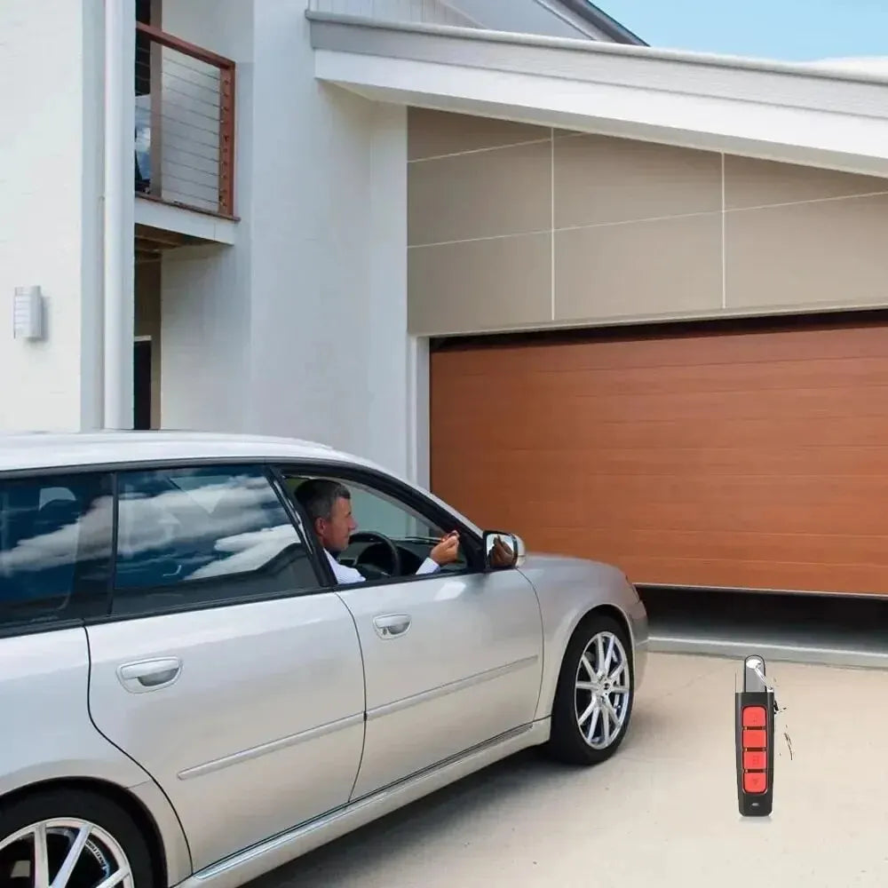 A person in a silver car uses the Universal 433MHz Wireless Remote Control For Garage Access to open a wooden garage door of a modern house.