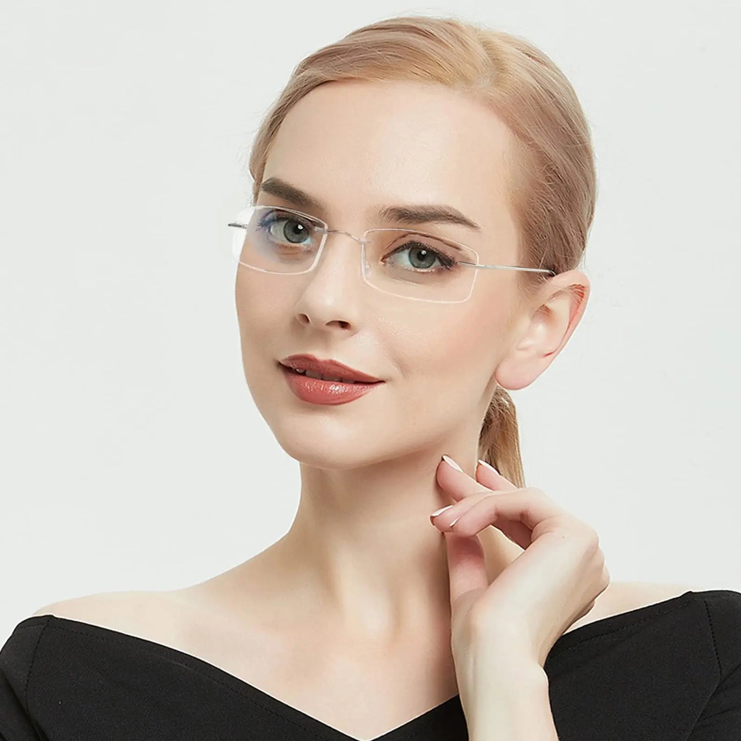 A person with light hair poses confidently against a white backdrop, wearing YINSQER Titanium Rimless Reading Glasses - Blue Light Blocking. They sport a black off-shoulder top, a subtle smile, and gently touch their collar with one hand.