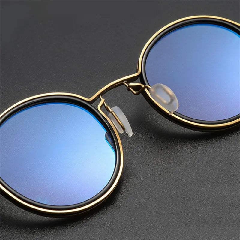 KLASSNUM Luxury Round Frame Reading Glasses feature reflective blue lenses and a thin gold frame on a dark gray background. They include adjustable nose pads for comfort and offer chic style with anti-blue light protection in elegant round frames.