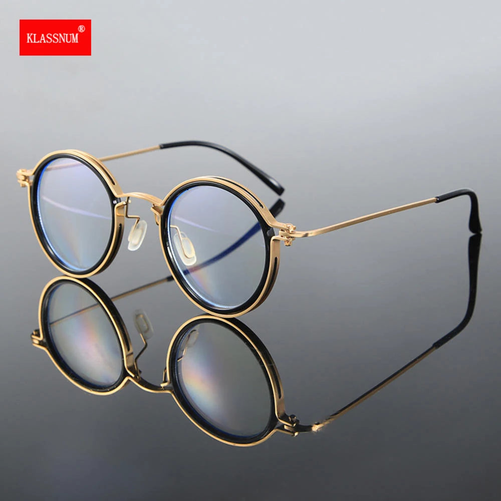 KLASSNUM Luxury Round Frame Reading Glasses with gold frames and blue-tinted lenses stand upright on a reflective surface, offering stylish looks and anti-blue light protection. The KLASSNUM brand name is visible in the top-left corner on a red background.