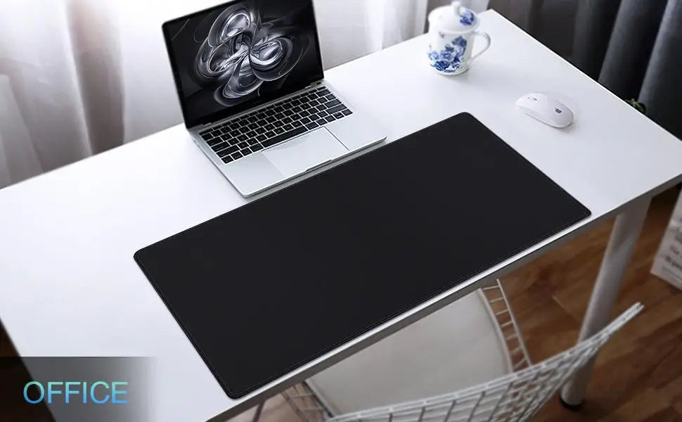 A white desk showcases a Ziyoulang Large Mouse Pad (800x300mm) with stitched edges, matching a laptop with a digital swirl design. Nearby, theres a white wireless mouse and a blue and white teacup. A white chair is neatly placed beneath for comfortable work sessions.