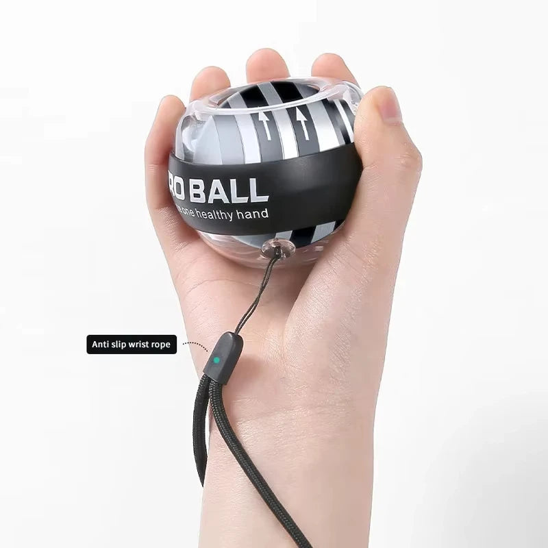 A hand holds a black and gray Gyroball Powerball Forearm Muscle Fitness Equipment, perfect for boosting wrist strength. An anti-slip wrist rope is securely attached to this device against a plain white background.
