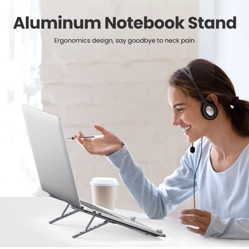 Smiling, a person with a headset gestures at an open laptop on the UGREEN Laptop Stand - Adjustable Foldable Aluminum. Above reads: Ergonomic design, say goodbye to neck pain. A coffee cup sits nearby.