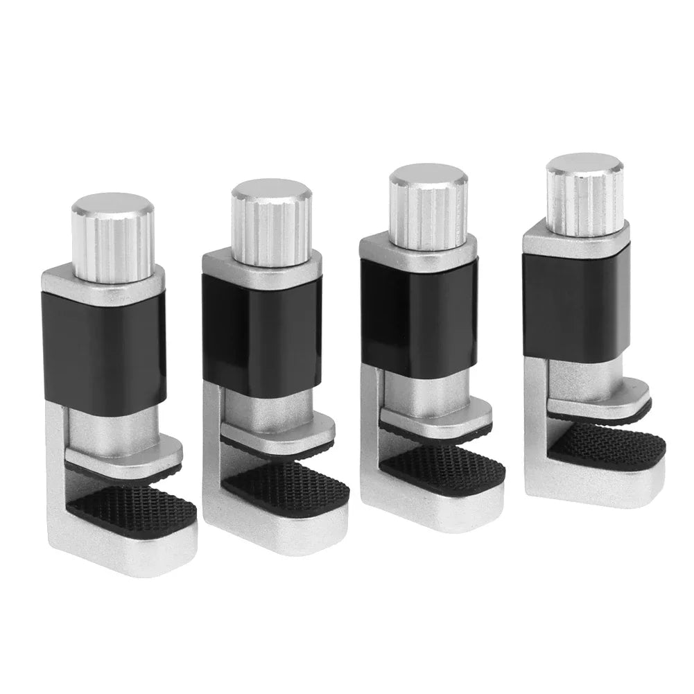 Four MOJOYCE Adjustable Alloy Clamps for Secure Mobile Repairs, with textured grips and a cylindrical screw on top for tightening, are aligned in a row. The clamps come in silver and black.