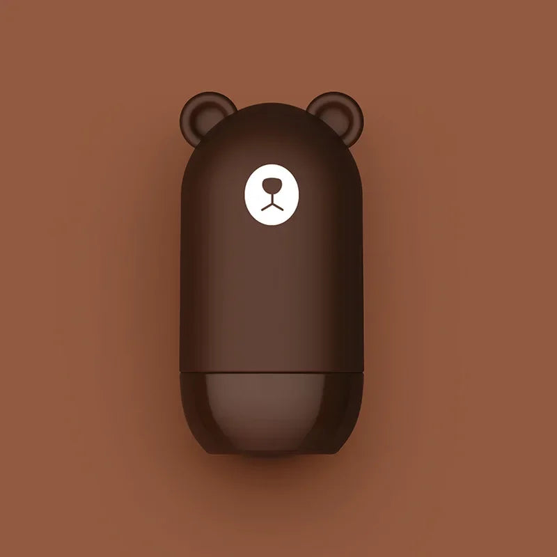 A brown capsule-shaped NoEnName Roller Stamp resembling a bear, with small round ears and a cute face, set on a matching brown background. Get this quick drying privacy seal now with free shipping!.