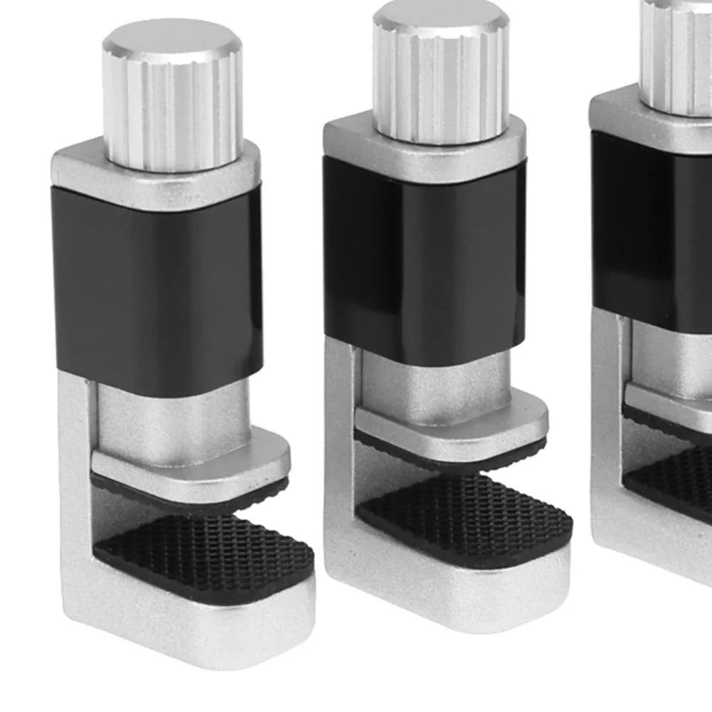 Close-up of three identical MOJOYCE Adjustable Alloy Clamps, ideal for secure mobile repairs. Featuring textured grips and cylindrical tops, they firmly hold objects in place, while the plain white background accentuates their sleek silver and black design.