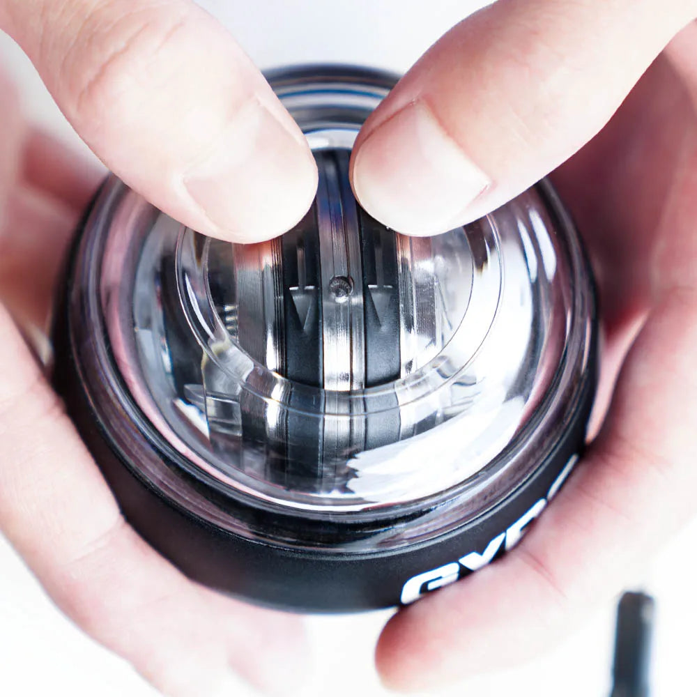 A close-up shows hands spinning the Self-Starting Gyro Ball for Enhanced Grip Strength. The transparent casing reveals the rotating mechanism as fingertips expertly maintain its spin, highlighting this essential home gym equipments design and function.