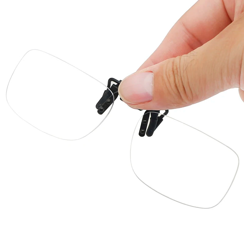A hand holds a pair of WALLY SKY Ultra-Light Anti Blue Light rimless, rectangular clip-on reading glasses with black clips. The clear lenses and simple design are elegantly highlighted against the white background.
