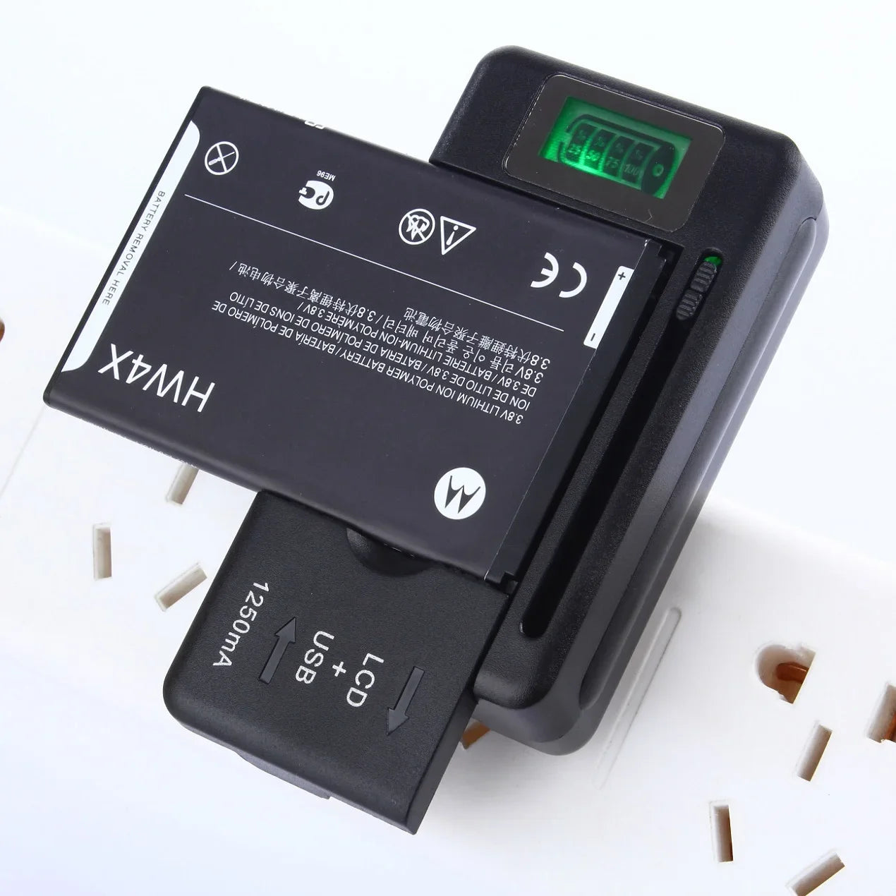 The YIBOYUAN Universal USB Battery Charger with LCD Indicator is plugged into a wall socket, charging a Motorola battery. Its green digital display glows, and this versatile black device features clear labels for its LCD and universal USB ports, ensuring compatibility with multiple devices.
