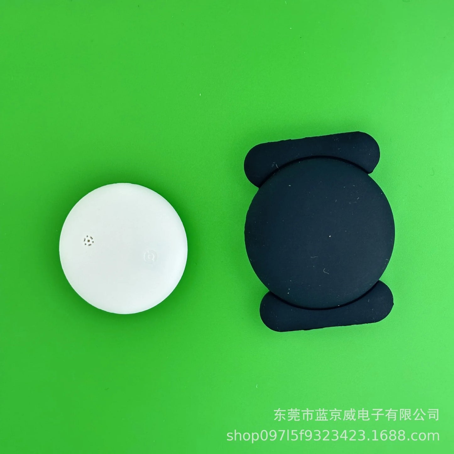 A white circular electronic gadget sits beside a black round-edged device on a bright green background, showcasing the NoEnName GPS Tracker - Bluetooth Locator for Pets with Global Precision Search. Chinese text appears in the bottom right corner.