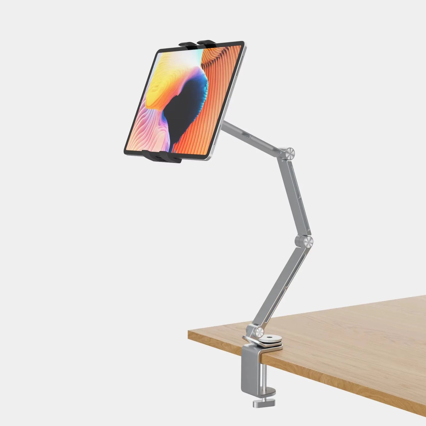 The Artpowers Adjustable Tablet Holder - Versatile Stand is clamped to a wooden table, displaying a colorful abstract design on the tablet. With universal compatibility, it features an adjustable arm and multiple joints for enhanced flexibility and positioning, resembling an adjustable stand.