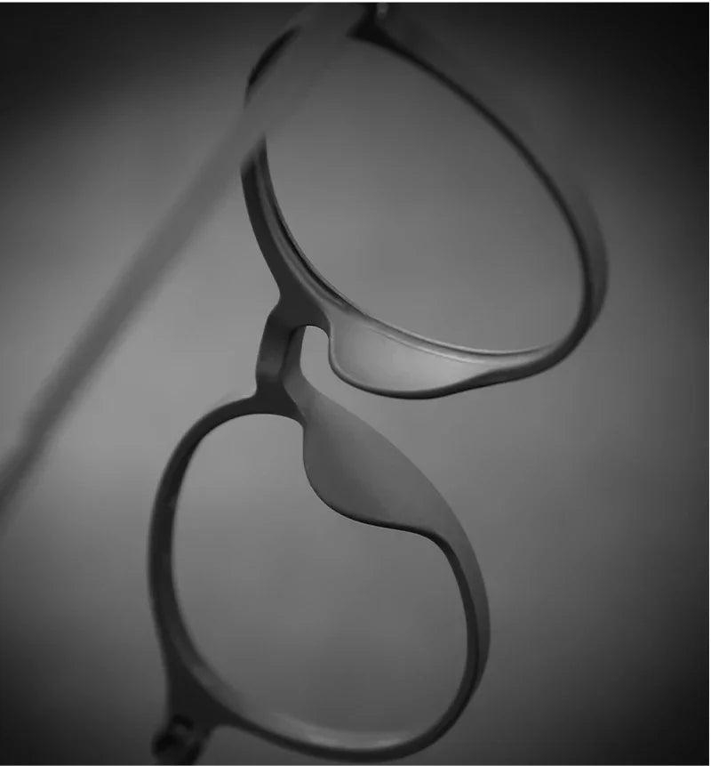 Close-up of OUTMIX Pure Titanium Anti Blue Light Reading Glasses featuring titanium frames against an abstract monochrome backdrop. The frames and lenses are in focus, while the blurred background adds a minimalist artistic touch.