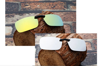 Two pairs of Honey Joe Polarized Clip-On Sunglasses, with UV400 protection, rest on tree stumps. One has reflective yellow-green lenses, the other mirrored silver. A rustic brick wall accentuates their stylish and protective design against harmful sun rays.