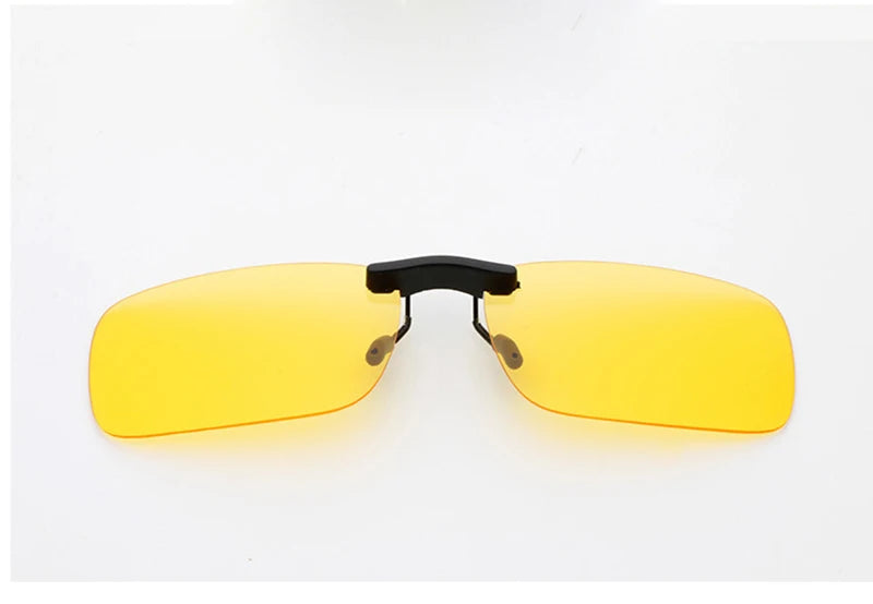 The Honey Joe Polarized Clip-On Sunglasses feature rectangular, slightly curved, yellow-tinted lenses with UV400 protection for night driving. Designed with a black frame to fit over regular eyewear, they offer enhanced eye safety against a plain white background.