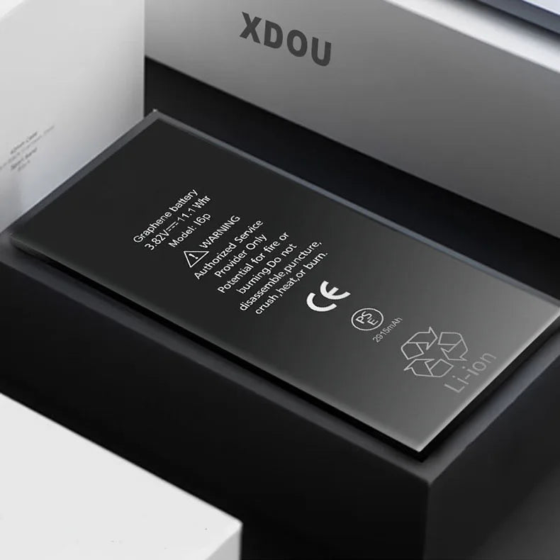 The XDOU Battery for iPhone SE 5-11 Pro offers 3800 mAh and 15 Wh for extended battery life. It features safety warnings, recycling symbols, and a CE mark. The rectangular graphene battery is designed for zero-cycle use and rests on a dark surface with light-edged surroundings.