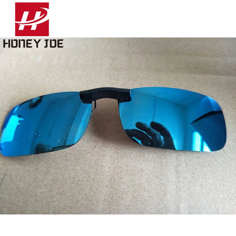 Honey Joe Polarized Clip-On Sunglasses with UV400 Protection rest on a light brown surface. The Honey Joe logo appears in the top left corner, and fingers and a phone subtly reflect in the lenses.
