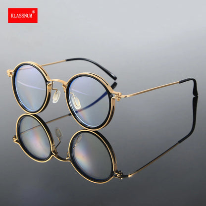 KLASSNUM Luxury Round Frame Reading Glasses with gold frames and blue-tinted lenses stand upright on a reflective surface, offering stylish looks and anti-blue light protection. The KLASSNUM brand name is visible in the top-left corner on a red background.