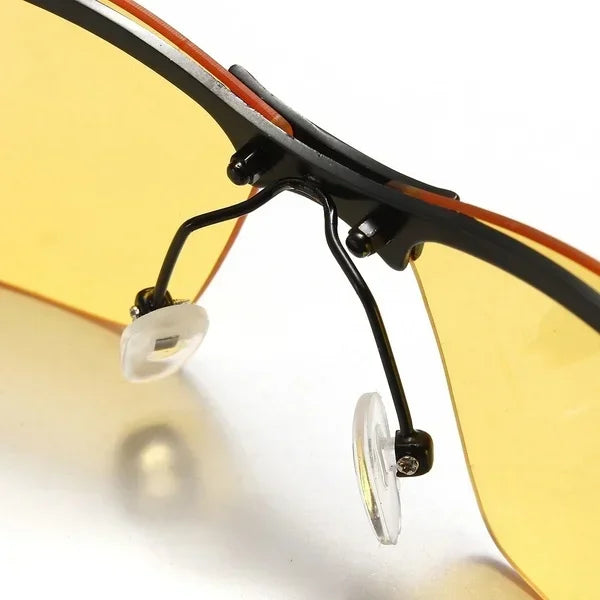 Close-up of HARKO Polarized Night Vision Cycling Sunglasses, showcasing yellow-tinted clip-ons with black metal frames and transparent nose pads, designed to fit over regular glasses. Ideal for outdoor adventures, the image highlights the hinge and connecting components.