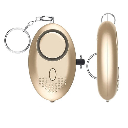 The 130dB Personal Safety Alarm Keychain offers a gold oval design with a keyring, featuring a circular button, LED light, and textured speaker on the front. It provides both front and side views for stylish self-defense.