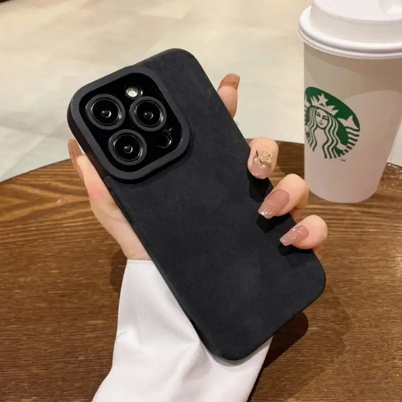 Luxury Matte Cortex Leather iPhone Case with Shockproof Protection displayed in a hand near a table with a coffee cup.