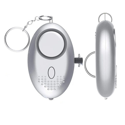 The 130dB Personal Safety Alarm Keychain has a silver oval design with a keychain ring. Its front features a large button and small speaker holes, while the side shows its slim profile. It activates a powerful 130dB alert for self-defense.