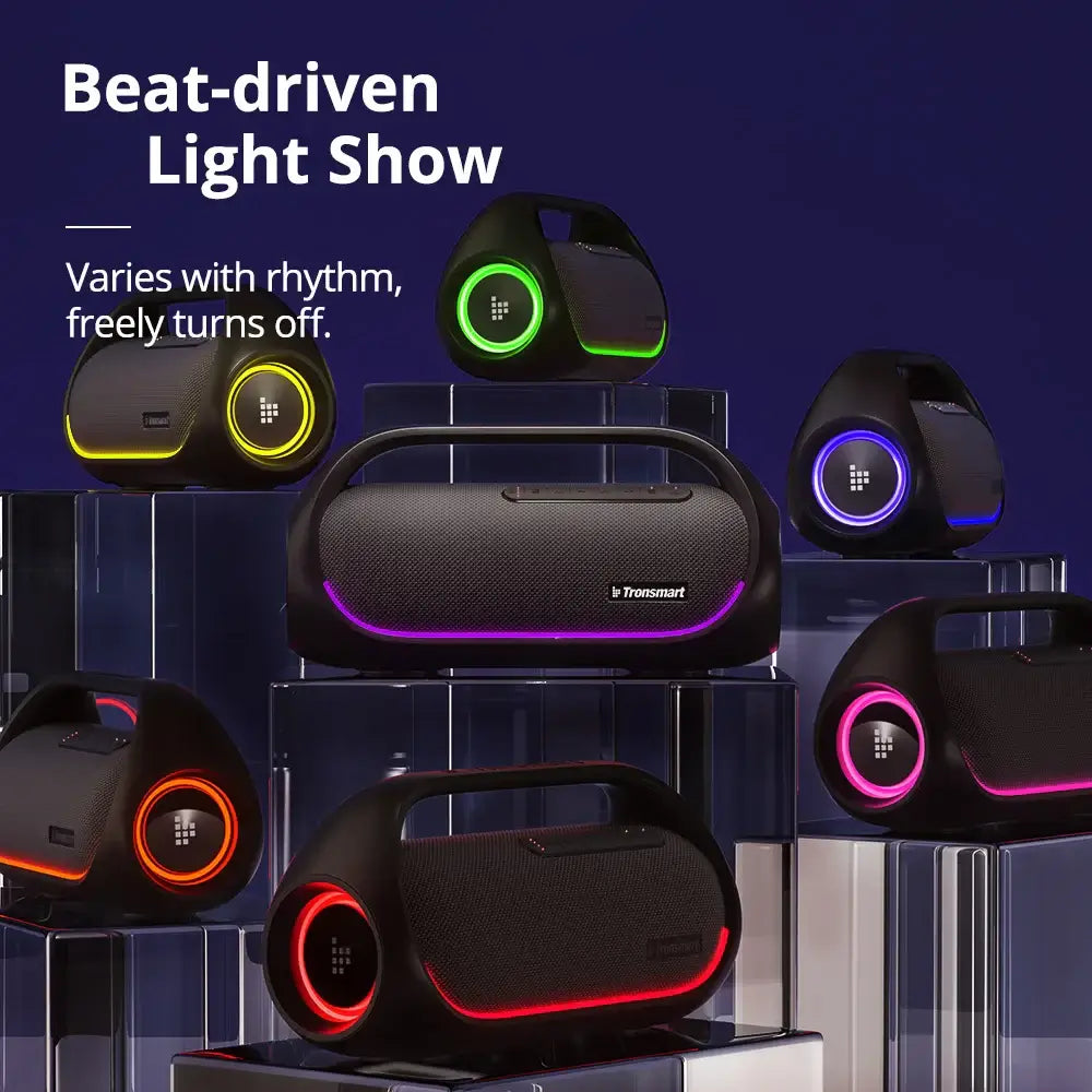 Tronsmart Bang Speaker with LED lights in various colors is displayed on clear pedestals against a dark background. Text reads: Beat-driven light show. 60W Bluetooth speaker with heavy bass, rhythm sync, and optional light control via app.