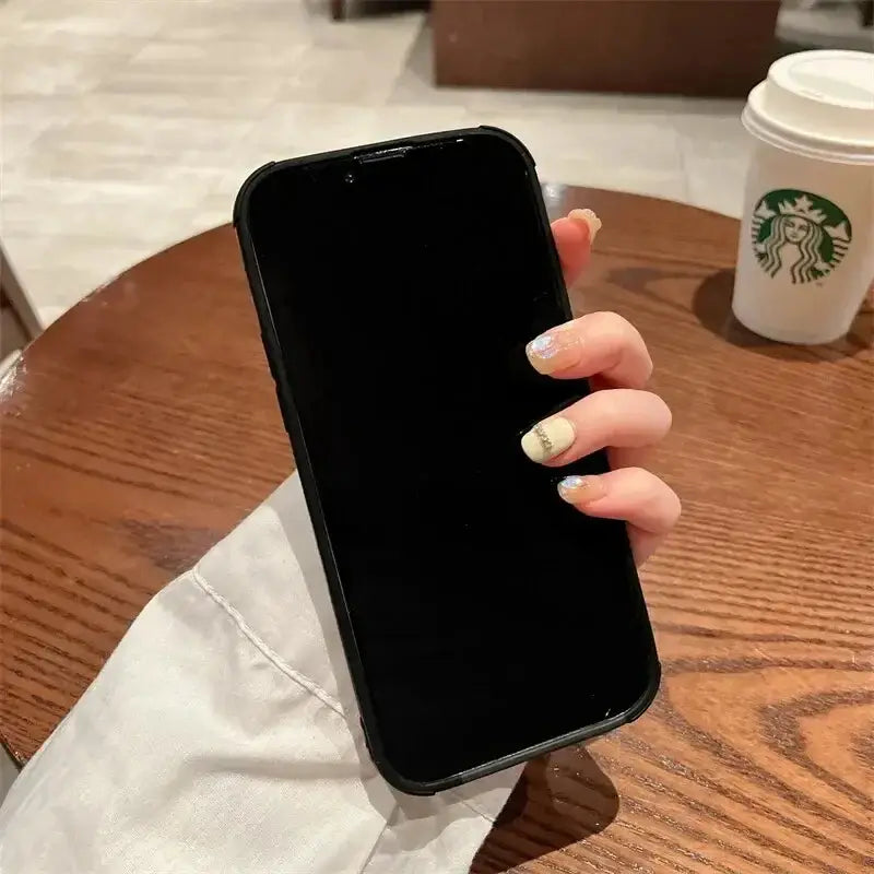 Person holding an iPhone with a Luxury Matte Cortex Leather Case, featuring shockproof protection, at a Starbucks location.
