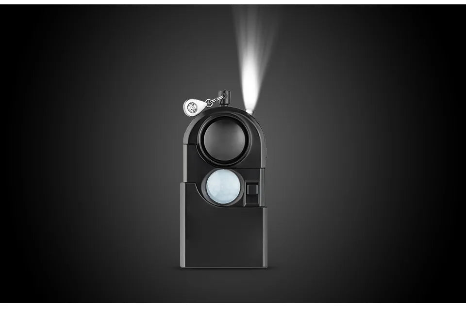 The KERUI Mini Motion Detector Alarm - 120DB Siren is a black, modern rectangular flashlight with a bright white upward beam, built-in motion detector alarm, metallic keyring attached, shown on a dark gradient background.