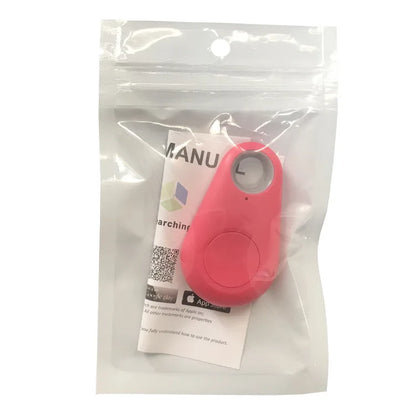 The Seamopar Mini GPS Tracker, a small red personal security alarm and Anti-Lost Bluetooth Key Finder, comes in clear plastic packaging. It has a round button and attachment loop, with a manual and QR code for setup visible behind the device.