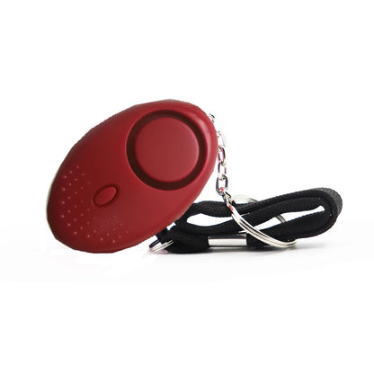 The 130dB Personal Safety Alarm Keychain, an oval red device with a central button, is affixed to both a keychain and black wrist strap for self-defense.