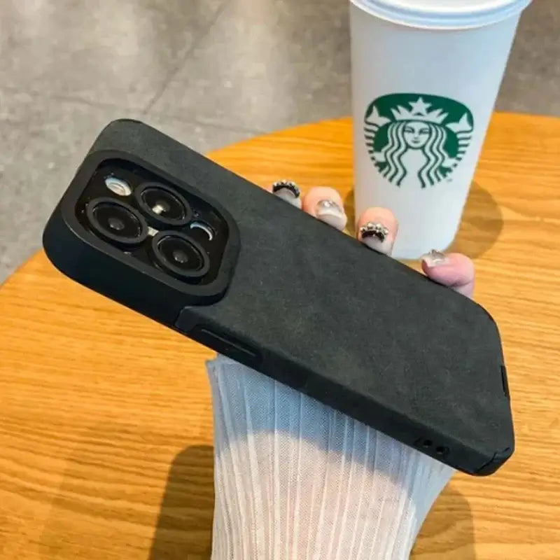 Luxury Matte Cortex Leather iPhone Case with Shockproof Protection shown in a coffee shop setting.